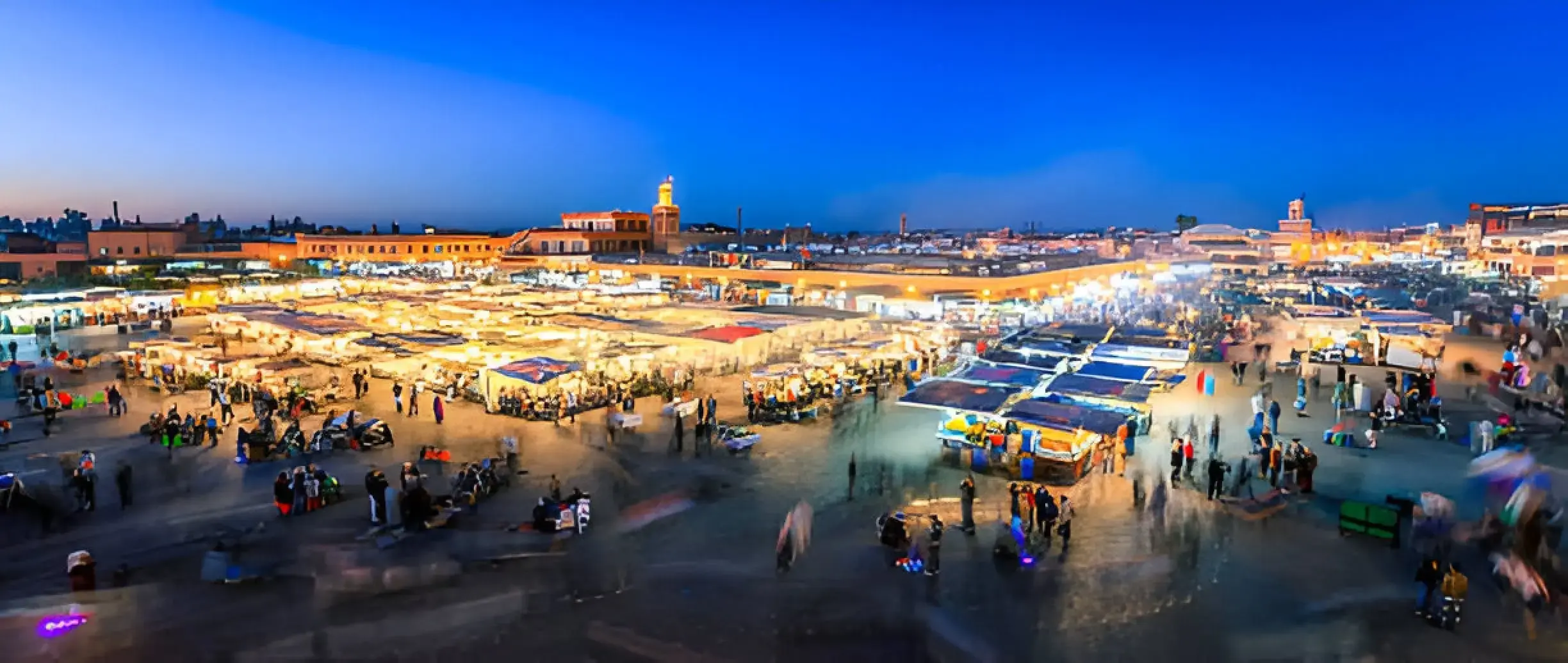 Best Time to Visit Morocco. A panoramic view of the vibrant Jemaa el-Fnaa square in Marrakech during a lively spring evening.