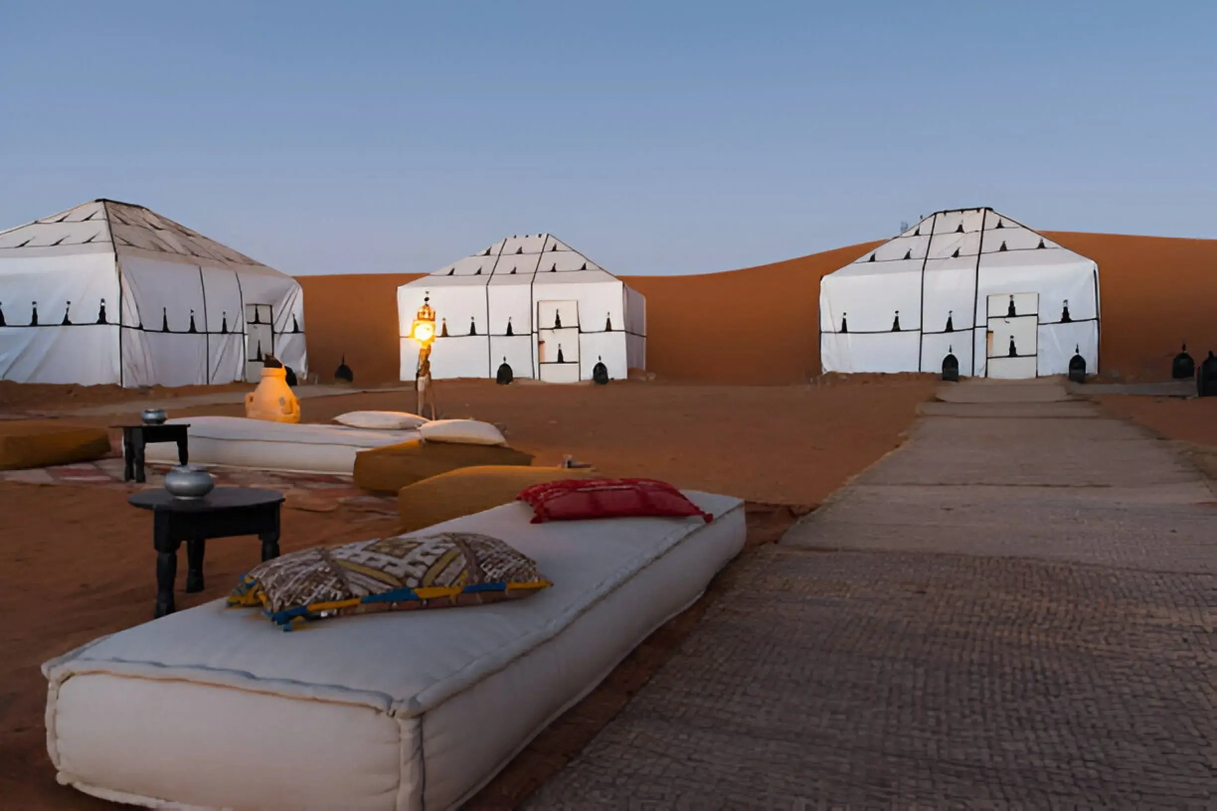 Private desert tour Morocco with luxury tents and camels in the Sahara at sunset.
